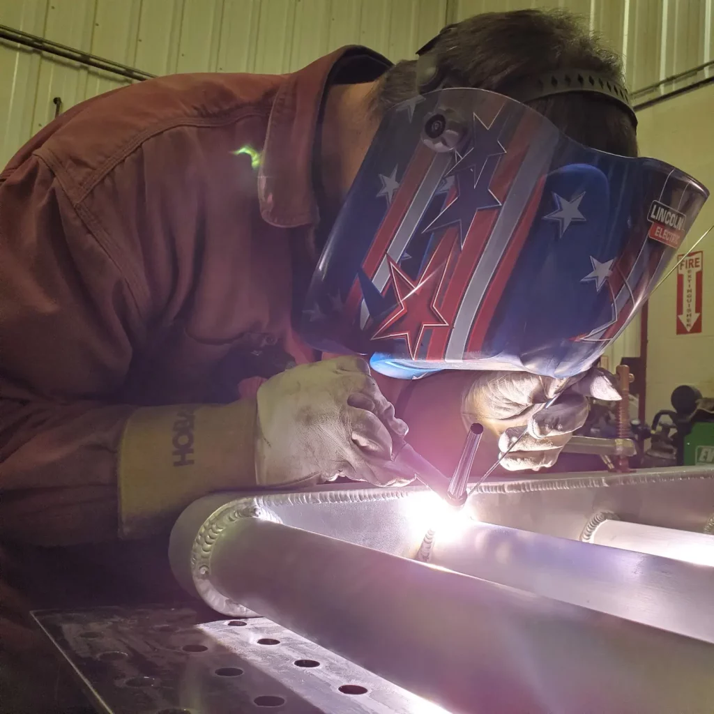 Employee welding metal tubes together